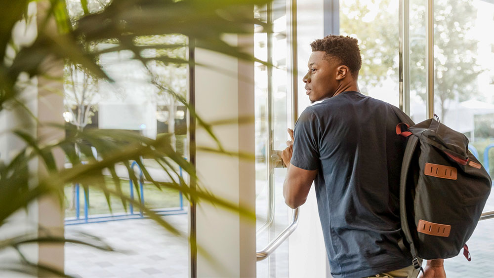 Young African American student walking out of the building.