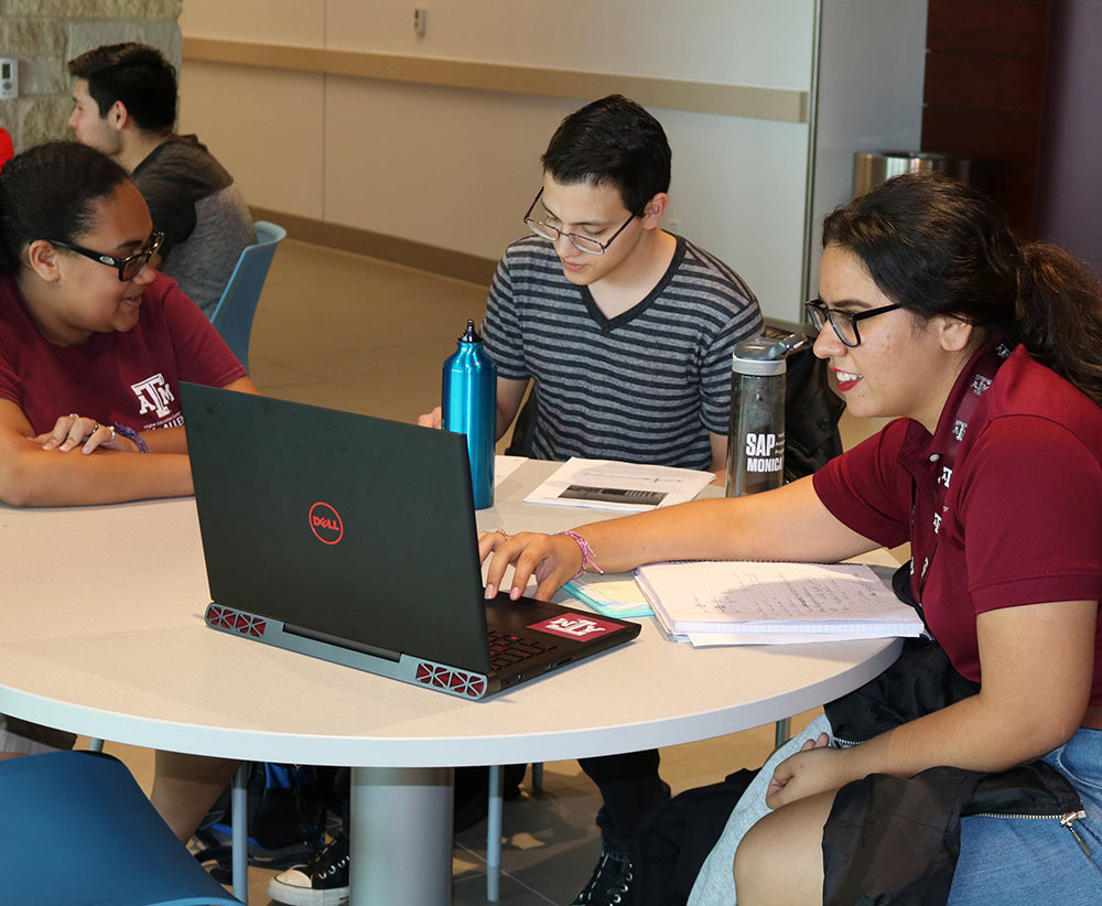 Three students work together at a table. 