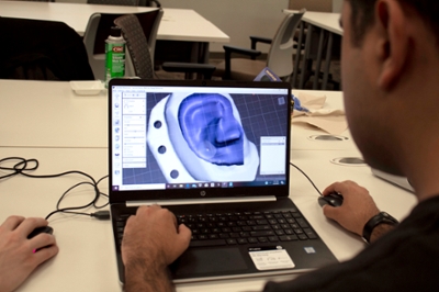 A close up a computer screen that shows a virtual version of an ear. Around it is a virtual half oval of metal with holes in it, signifying the device to help reform the ear.