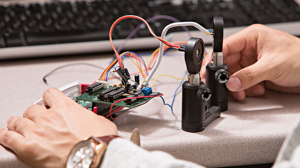 Experimental optics are hand wired to a circuit board, on a test bench.