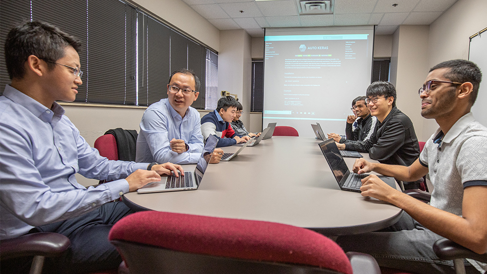 Image of students and professor having discussion around a table.