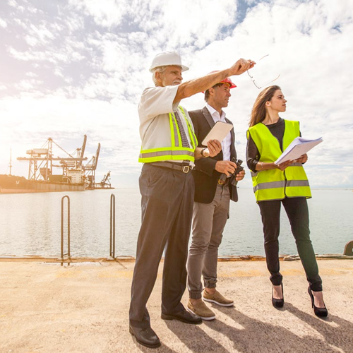 Industry workers pointing out something to a faculty member near an oil rig.