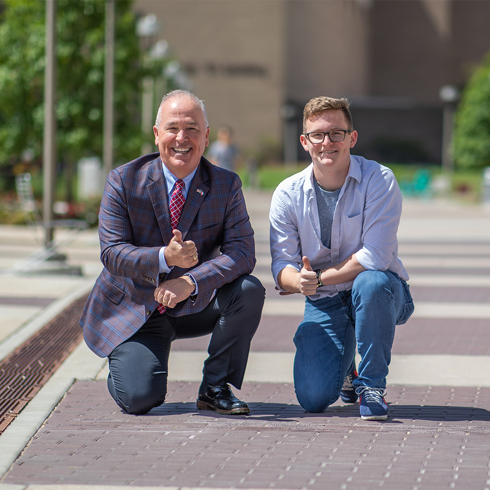 Daryl Heath and grandson bend down and throw up a "Gig 'em" near their bricks.