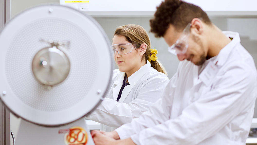 Two students work with machinery in the materials lab.