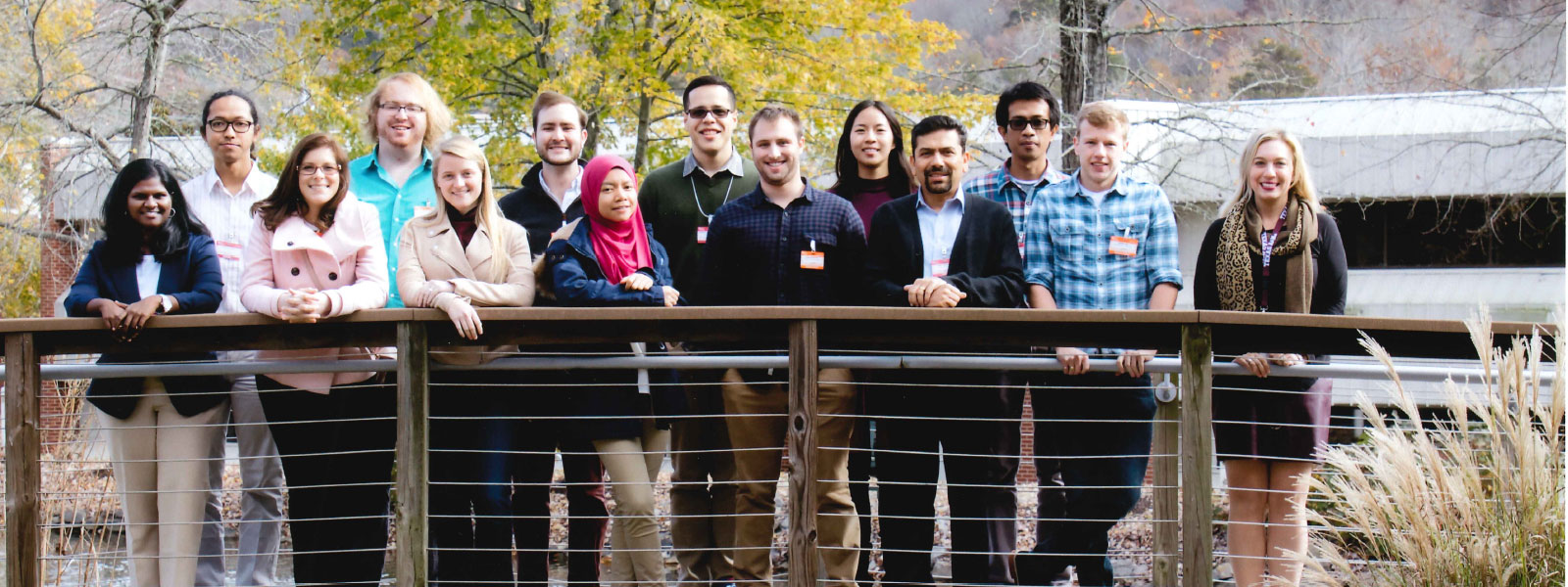 Group of men and women standing on bridge on a sunny fall day.