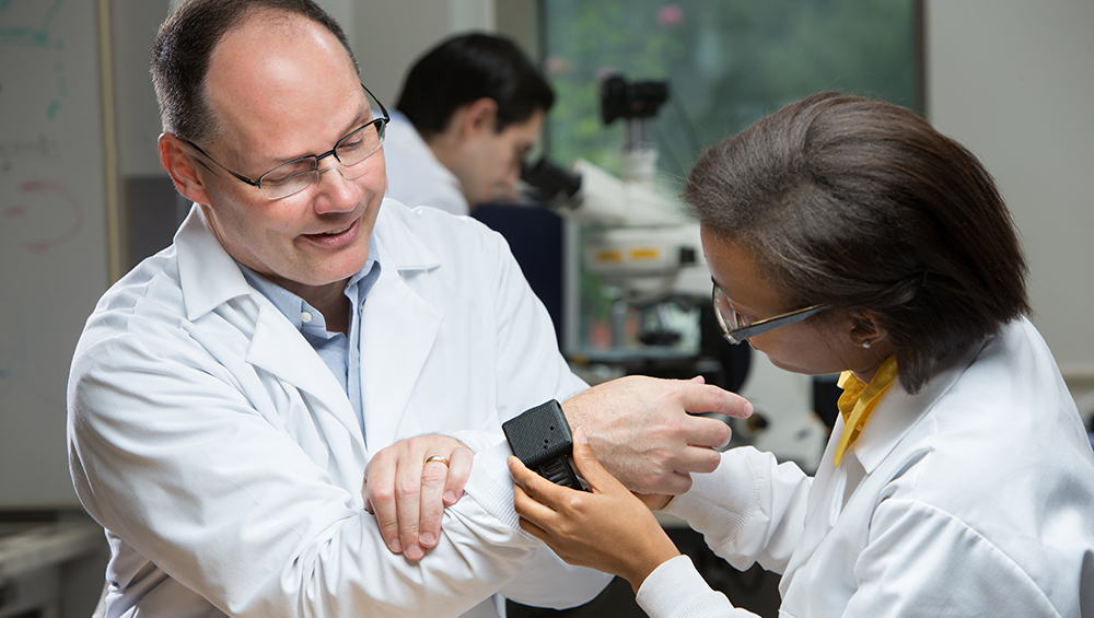 Dr. Cote and a graduate student display a smartwatch prototype.