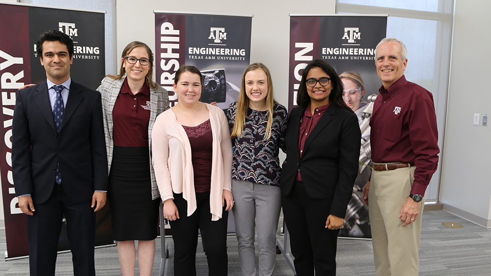 Student winners and mentors pose in front of banners 