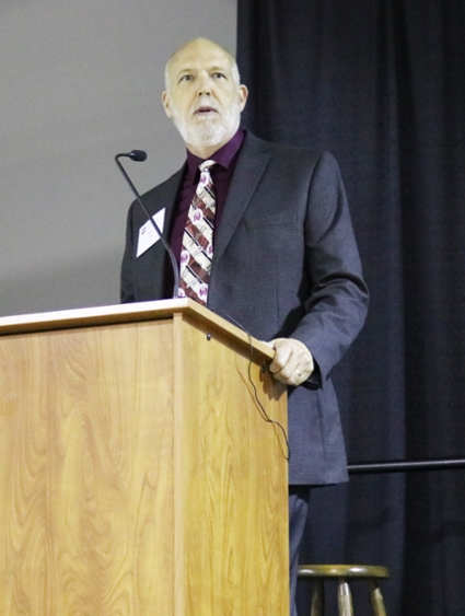 Brent Lyons stands at podium. 