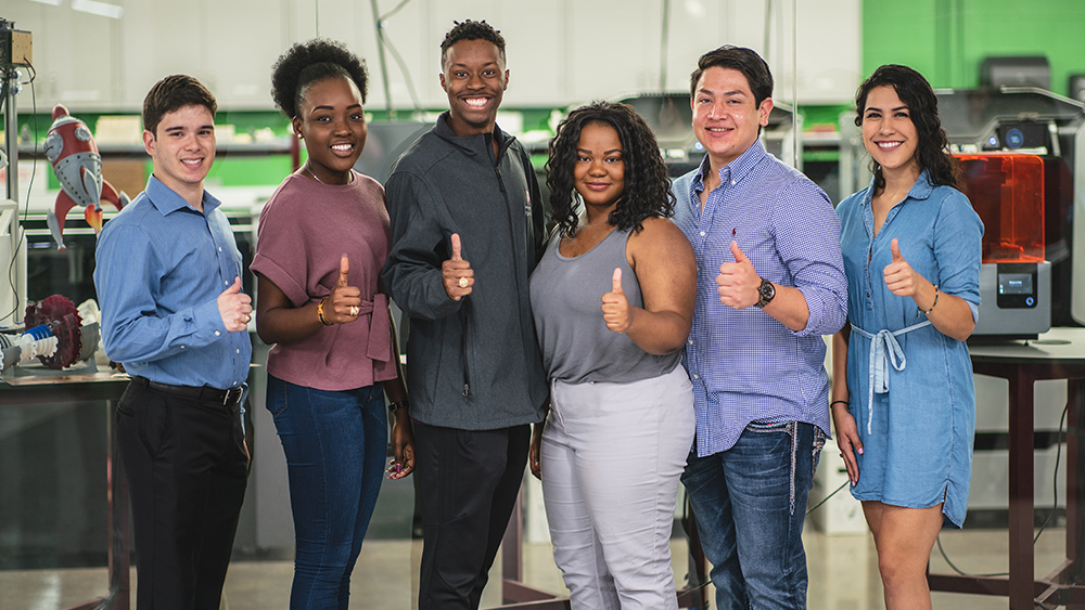 Six students pose for a photo with thumbs up