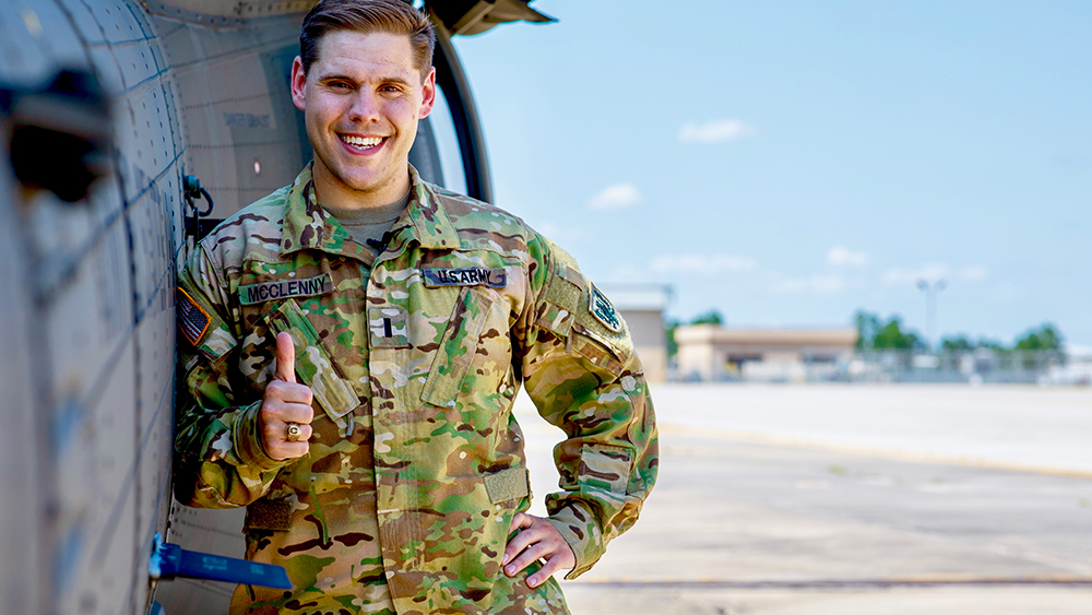 Levi McClenny stands in front of a black hawk helicopter 