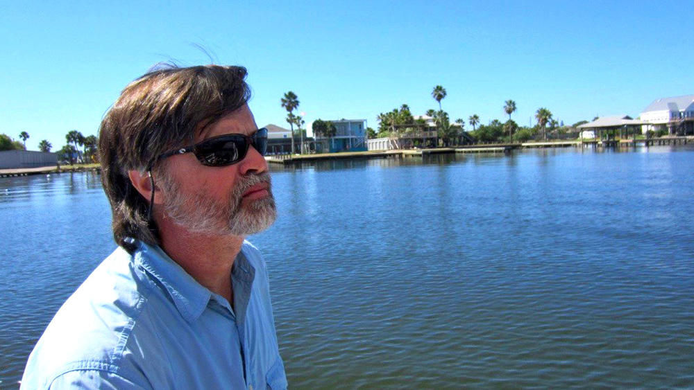 Dr. Sweetman sitting in a boat looking at the open water with the shore in the background.