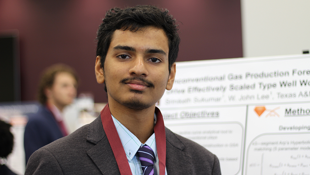 Sriniketh Sukumar standing proudly in front of undergraduate summer research program project poster