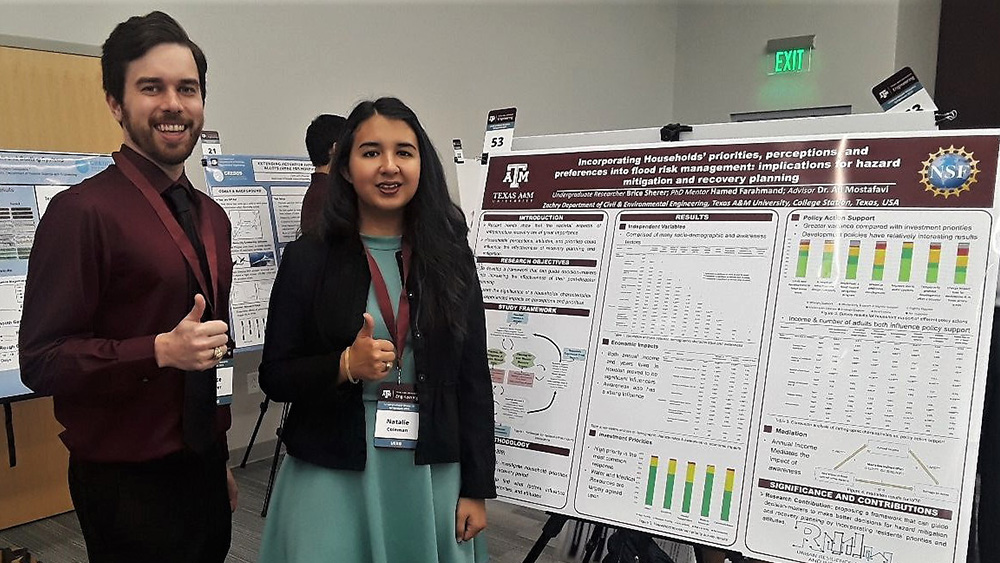 Brice Shrere and Natalie Coleman stand in front of their research poster with the thumbs up sign.