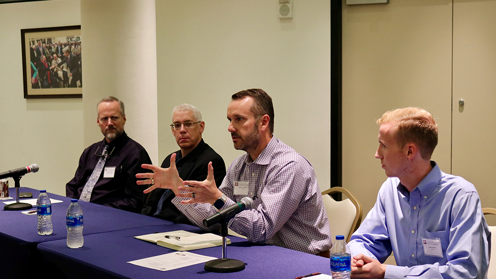 Four individuals sitting and speaking as part of a panel. 