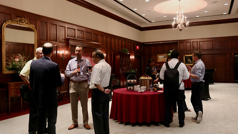 Individuals stand and speak during a reception. 