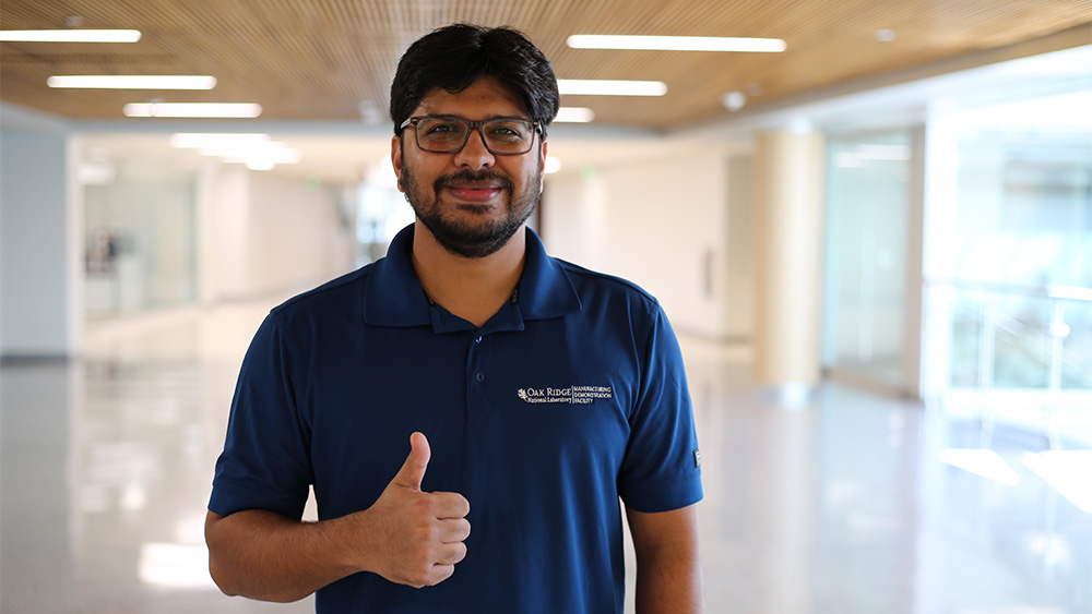 A man poses for a photo in a hallway with his thumb up