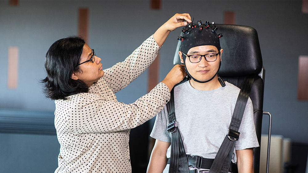 Professor adjusts monitors on students head. 