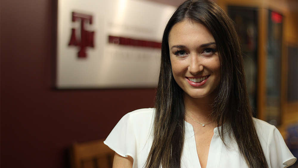 Lauren Borden standing in front of Harold Vance Department of Petroleum Engineering sign in Richardson building on Texas A&M University campus