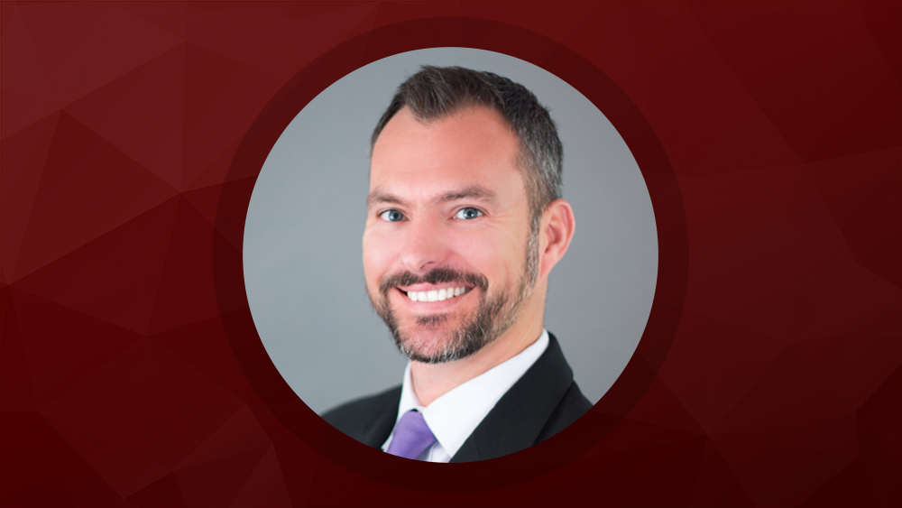 Headshot of Tim Daugherty with maroon background