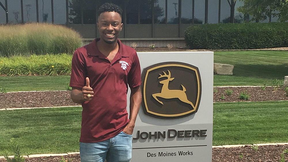 Zach Reece stands in front of John Deere sign. 