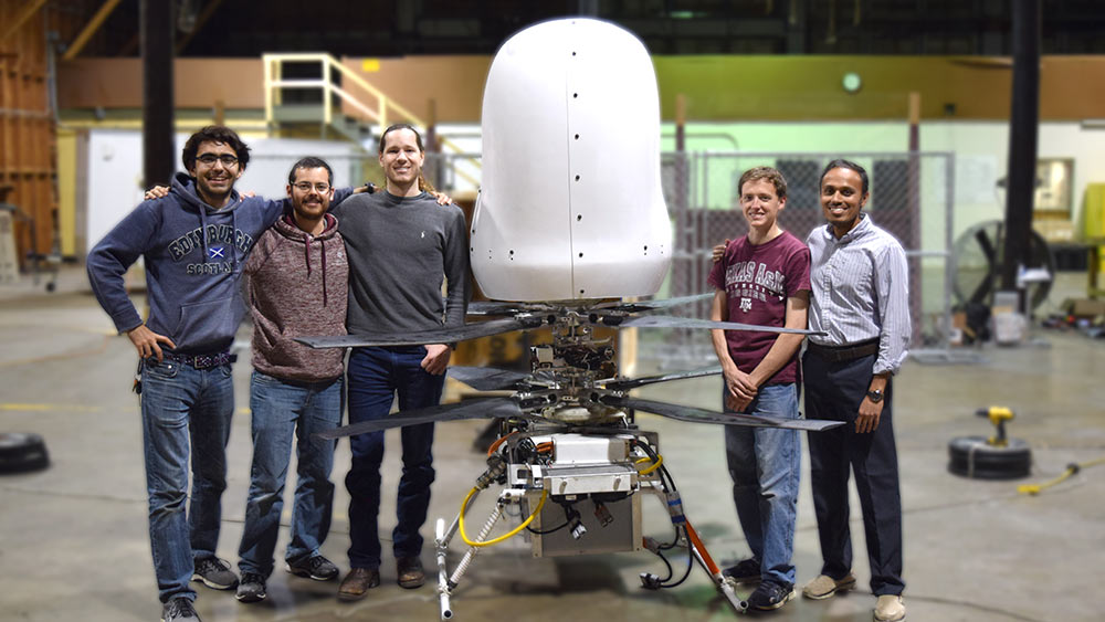 Five engineers stand smiling next to their prototype of a personal flying vehicle. 