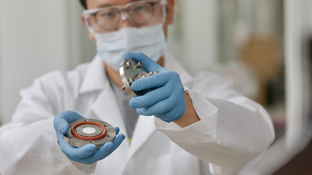 A male student in a laboratory holding a platform containing the polyimide membrane.