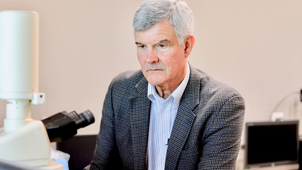 Dr. George M. Pharr looks into a microscope in the lab.