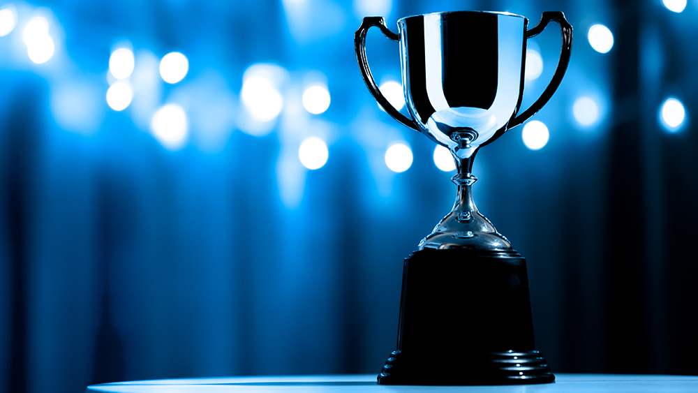 Silver Trophy in the dark on the abstract blurred light blue background.