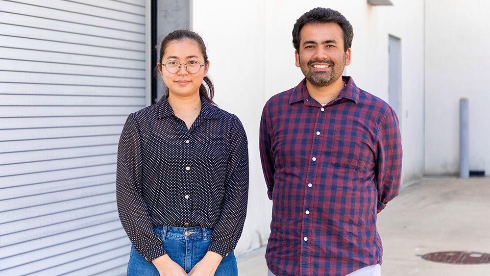 Kartik Kumar Rajagopalan and Xiuzhu Zhu stand next to each other outside next to a building.