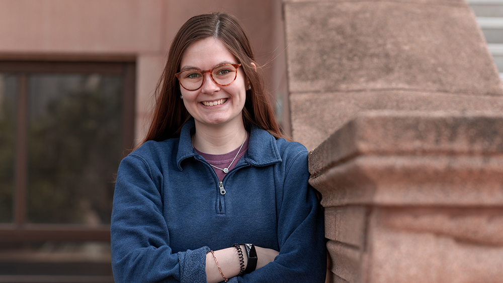 Suzanne Peterson stands with her arms crossed in front of a building.