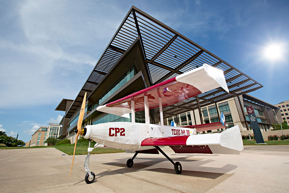 Red, white and blue Texas flag-themed biplane remote-controlled aircraft outside in front of Zachry Engineering Education Complex.