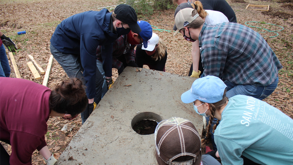 A group of students lifting a concrete latrine