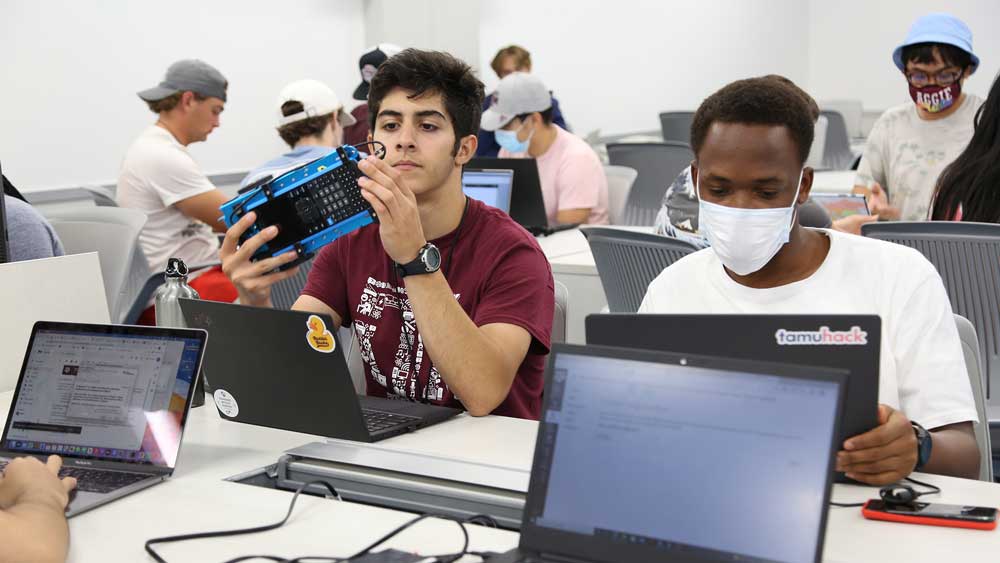 Guy with a calculator rover next to guy on laptop.