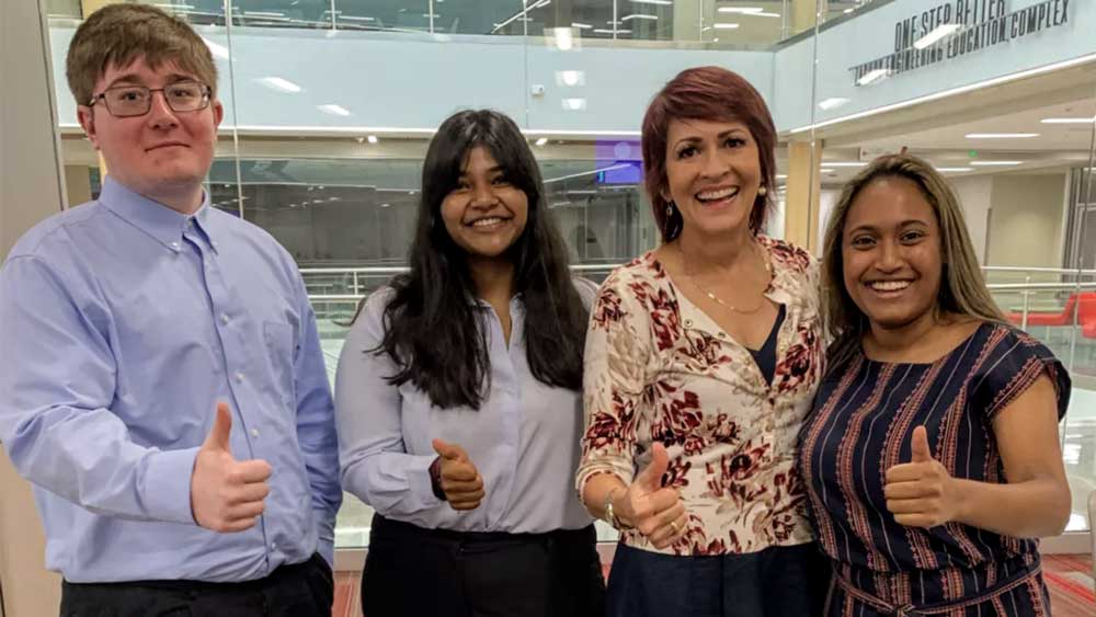 3 women and a man pose with a thumbs up