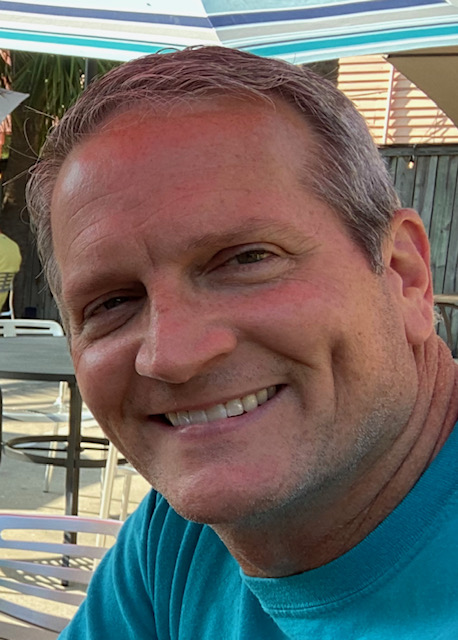 Edward "Nick" McGowen '93 smiles in a blue t-shirt.