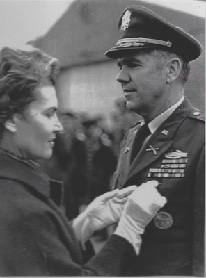 A wife pins a medal to her husband's military uniform.