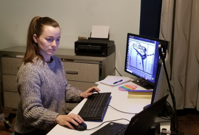 A female engineer sits at a home office, working on the computer.