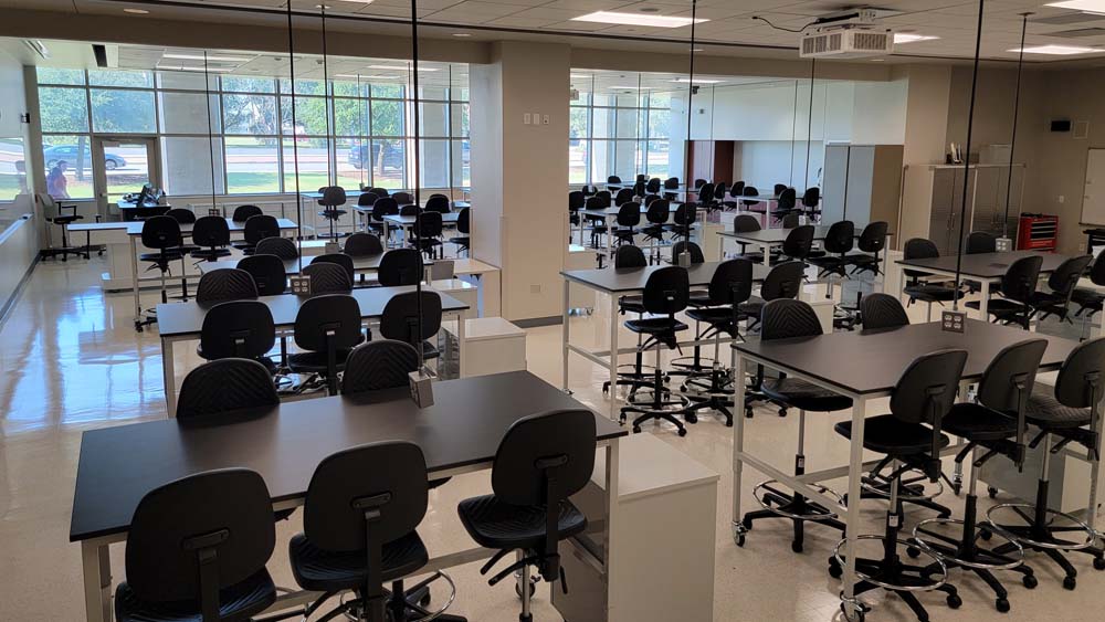 A design room complete with team tables and chairs. Large windows let in natural light