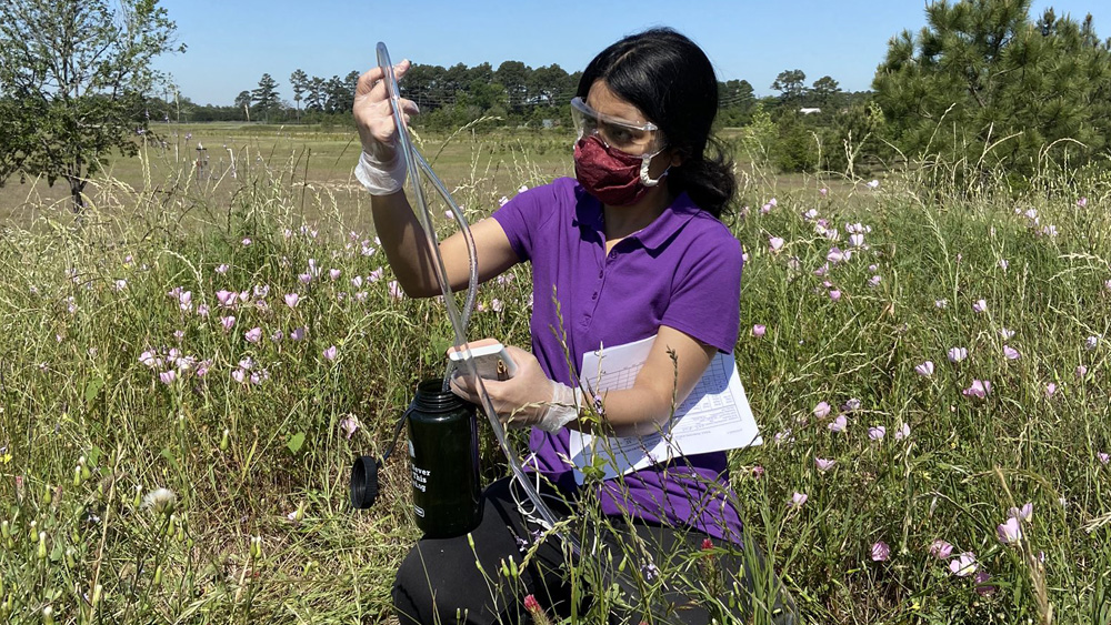 Student with a mask and goggles in a field 