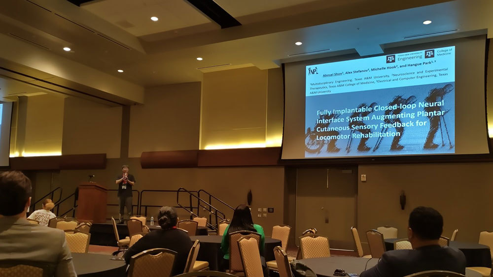 Male student on stage holding microphone explaining his presentation