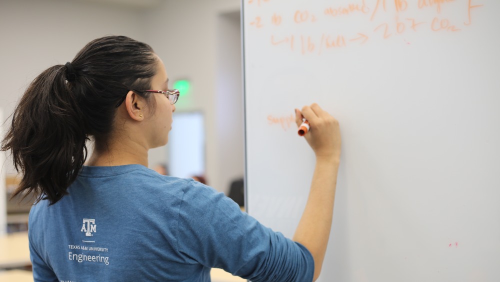 Student is writing on a white board at the IFTP 2022 first round.