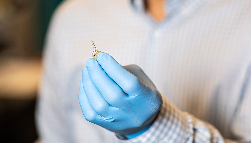 Hand with glove holding tiny wireless device