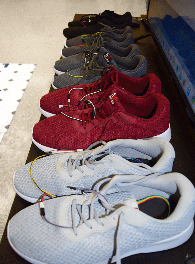 Row of five pairs of varying-colored shoes equipped with sensor wires.