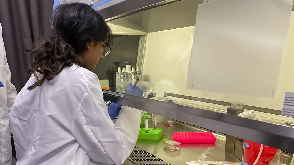 Richa Kalari labels samples under a glass partition in a lab