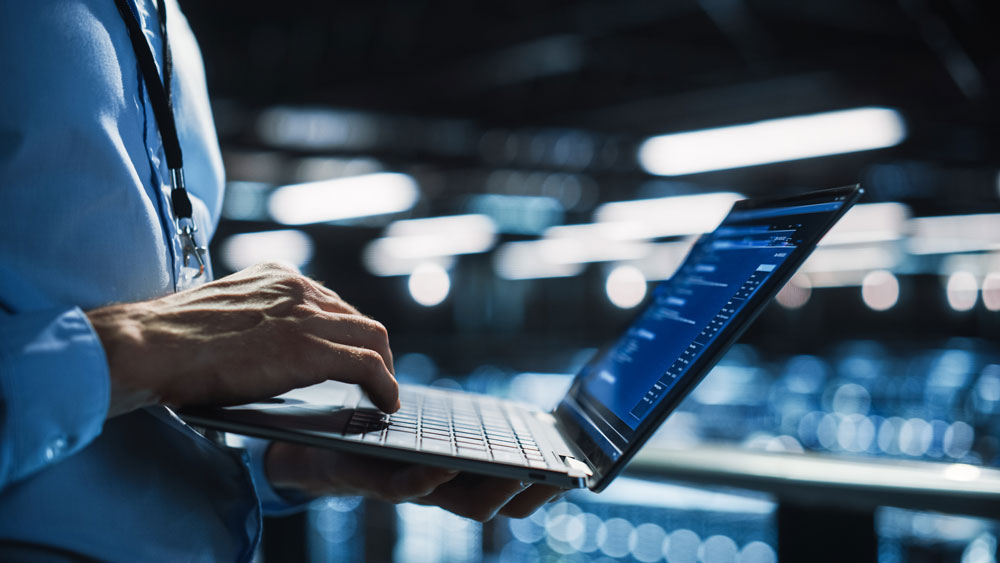 Closeup of a computer programmer’s hand working on a laptop.