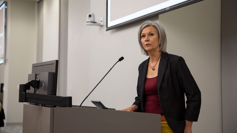 Becky Wilkes speaking at a podium.