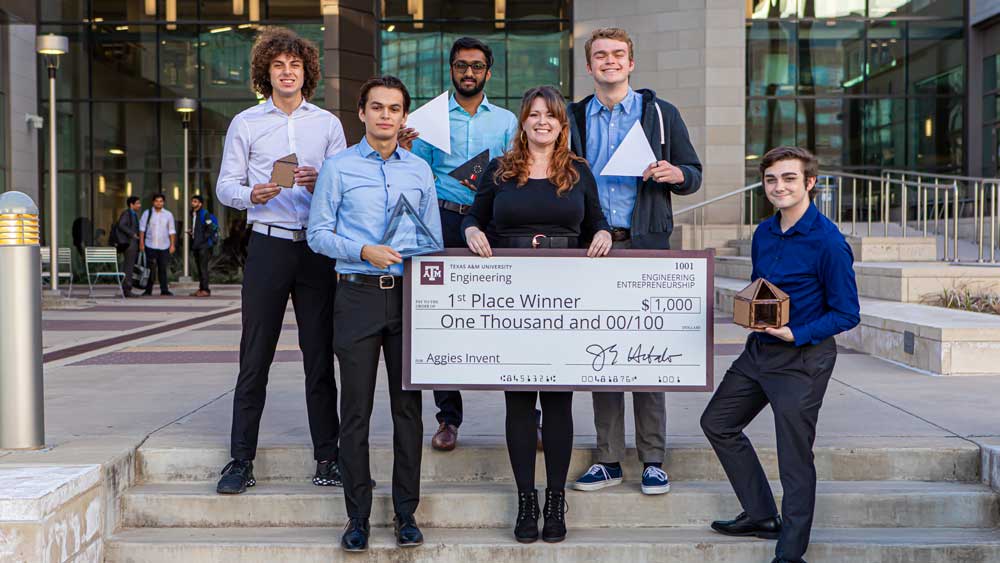 Team DisPlace members stand holding their $1,000 check and miniature structures.