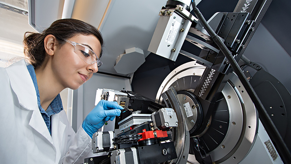  Dr. Hande Ozcan wearing safety goggles, a white lab coat and gloves, testing an experiment in an X-Ray machine.