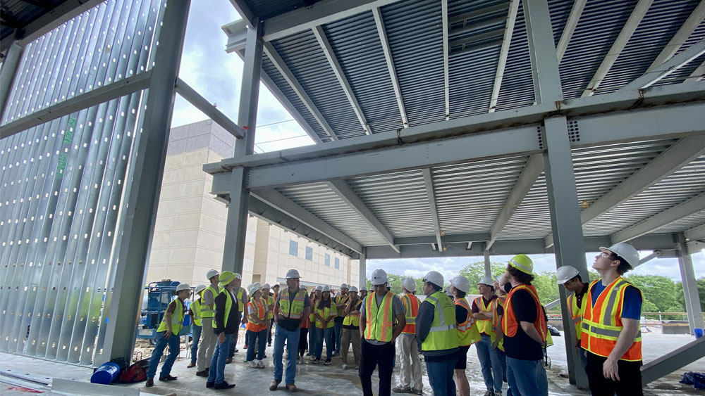 A group of people in vests and hard hats at a construction site.   