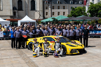 A group of people stand around a yellow racing car. All of them are wearing cowboy hats.